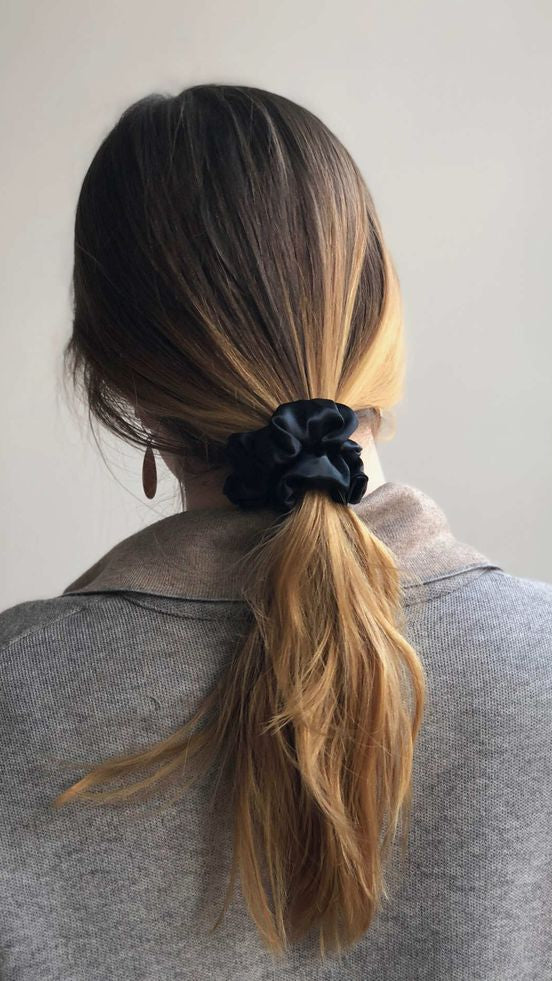 Zwarte zijden scrunchie gedragen in een lage paardenstaart voor haarvriendelijk stylen